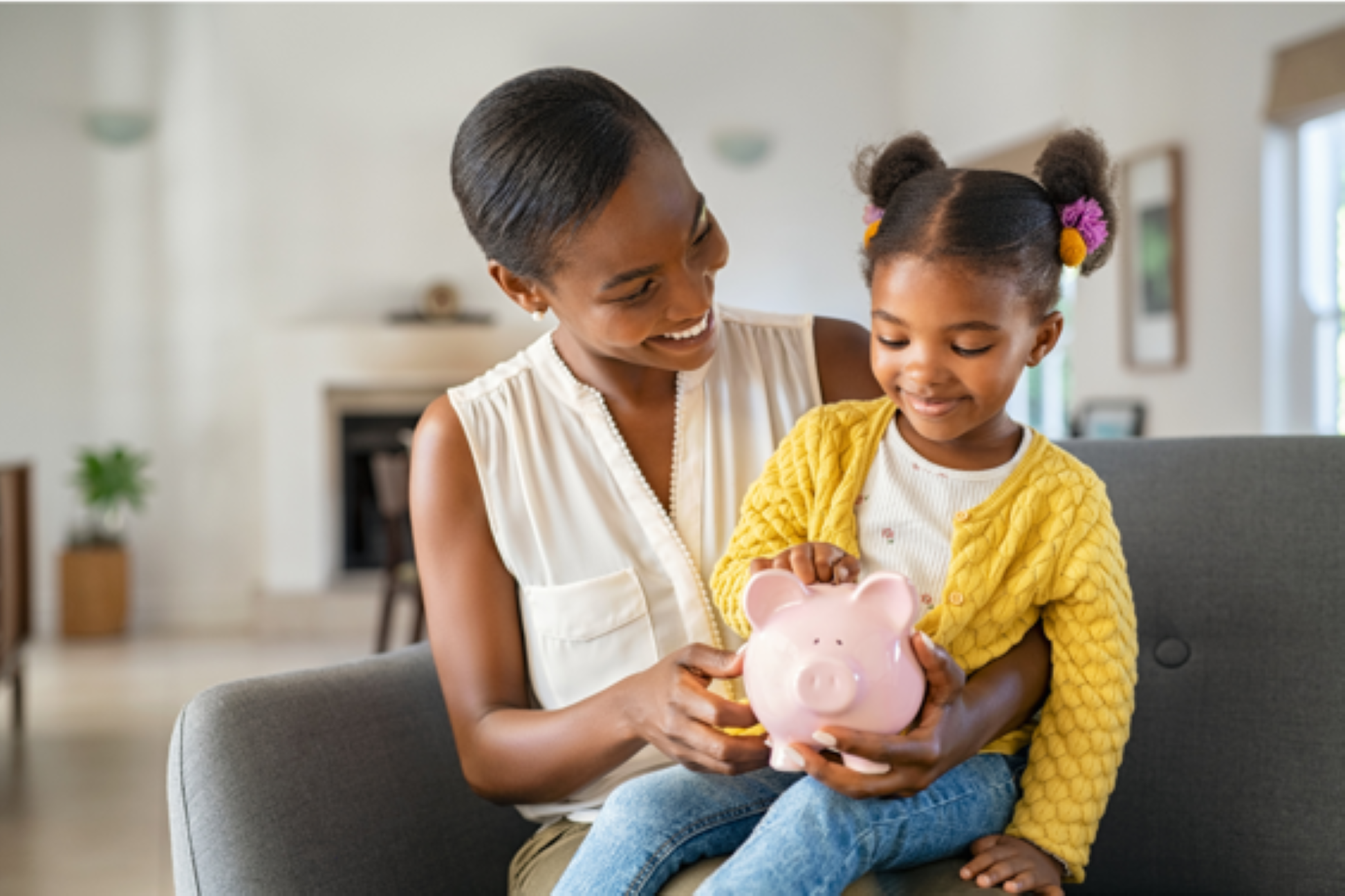 African American mother with child on her lap holding a piggy bank